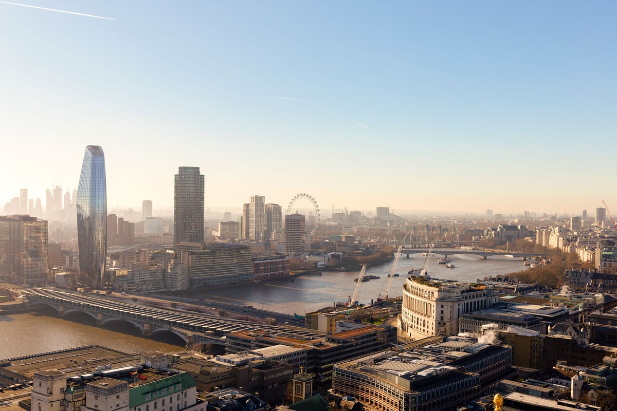 Daytime panoramic view of London with skyscrapers, the London Eye, bridges over the Thames River, under a clear sky.